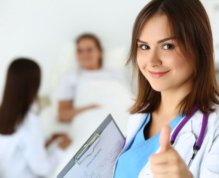 44401567 - smiling female medicine doctor holding document pad and showing ok sign with thumb up at ward wile round.